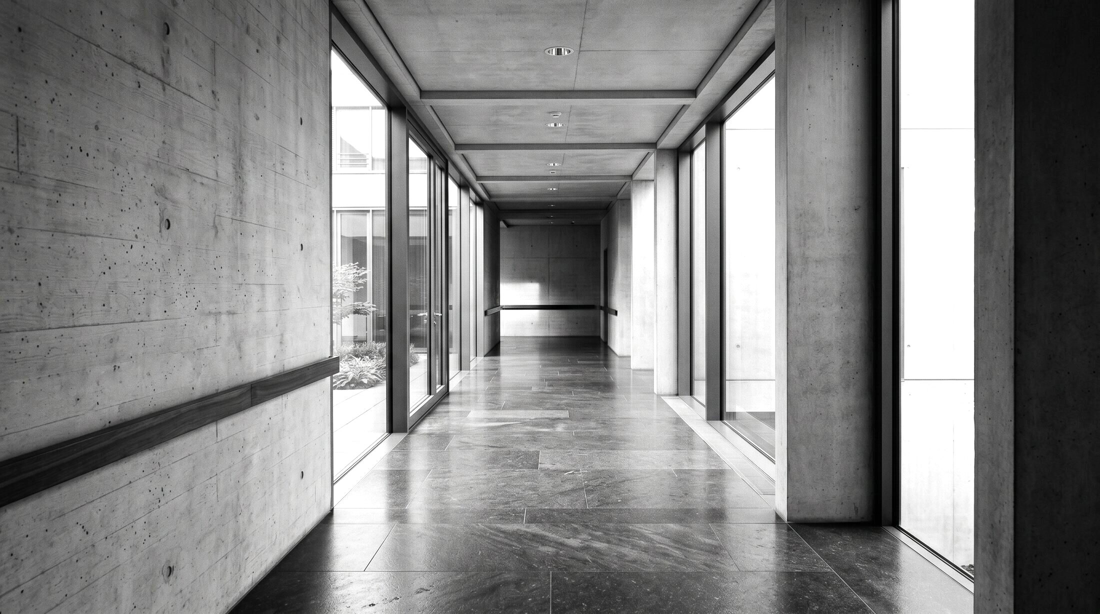 Schwarz-Weiß-Aufnahme eines modernen Architekturflurs aus Beton und Glas